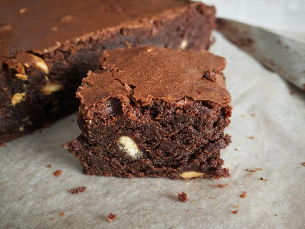 Slice of chocolate brownie showing fudgey centre and crunchy top