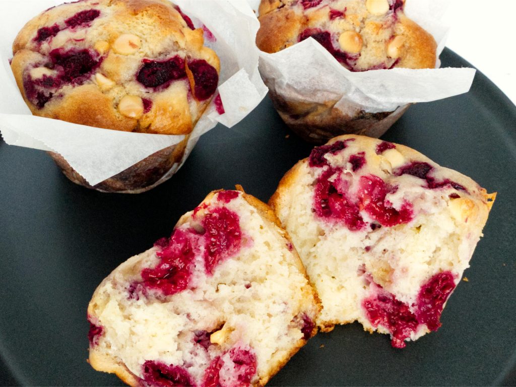 Raspberry and white chocolate muffin torn in half showing muffin filling