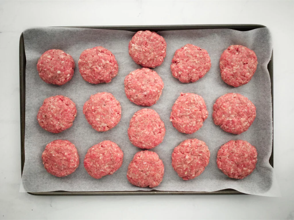 Cheeseburger slider patties on a tray ready for cooking