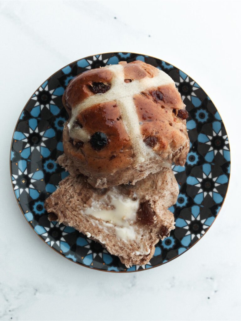 Hot cross bun served on a plate with butter