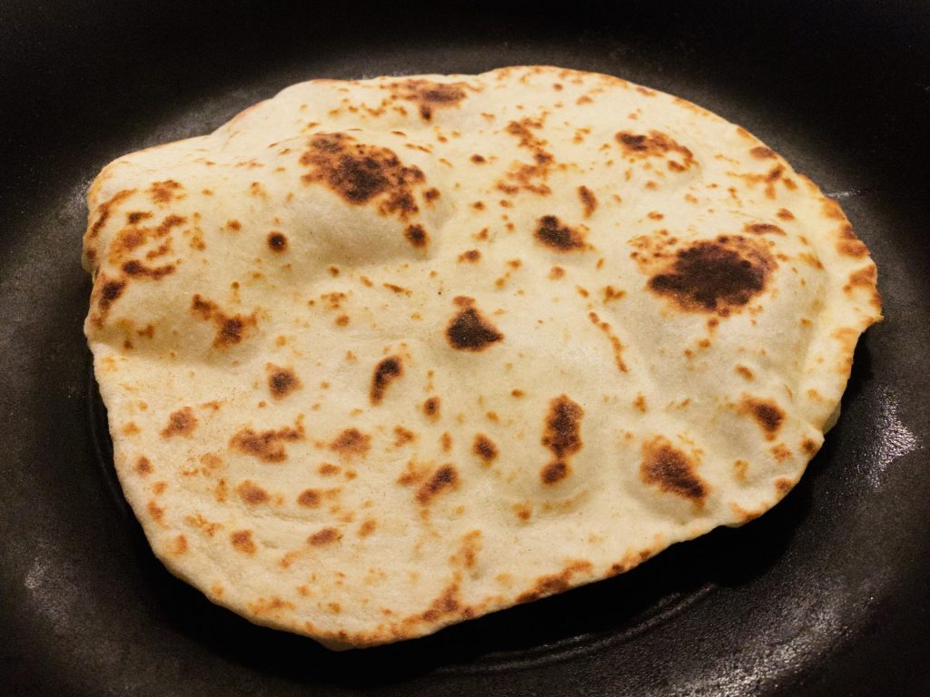 Freshly cooked flatbread in frying pan.